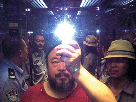 Self-portrait of Ai Weiwei in a room with a mirror behind him, and the flash of the camera above him.