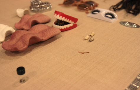 A variety of items, including three teeth, a cherry stem tied in a knot, and two pairs of sum glasses, are placed on a beige-colored mat.