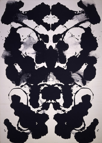 An abstract painting comprised of splotches of black ink that is symmetrical across a vertical axis down the center of the painting.