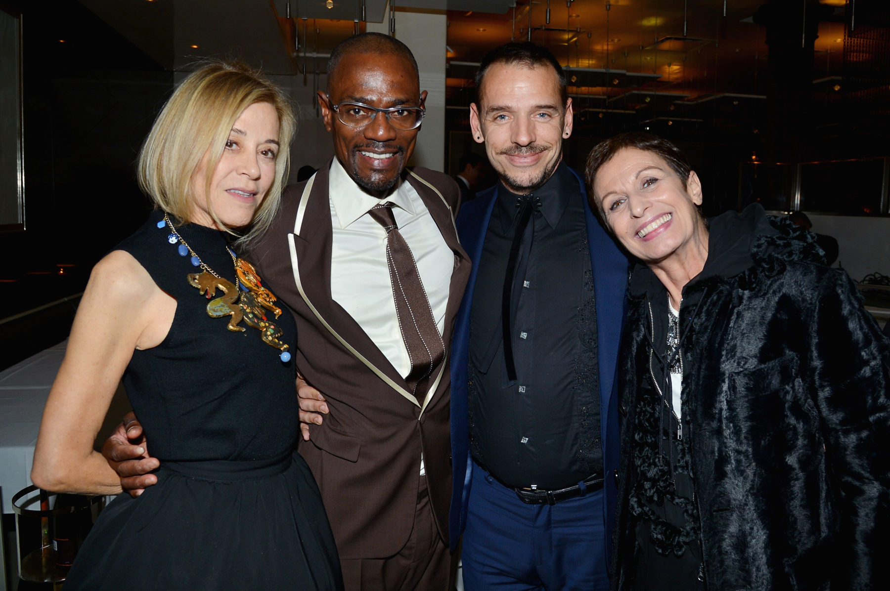 Four people standing in a row, smiling. The two men in the middle are wearing suits, the woman on the left is wearing a black dress, and the woman on the right is wearing a black jacket. The people left to right are Paige Powell, Kenneth Ard, Basil Twist, and Alba Clemente.