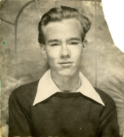 Andy Warhol as a teenager, photographed at a professional studio, wearing a dark colored sweater and light colored dress shirt