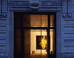 A view of the front facade of the Warhol Museum through which a large print of Andy Warhol can be seen.