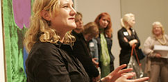 A clapping woman stands among a group of attendees at the opening of the Warhol: Immortal exhibit in New Zealand.