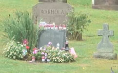 Andy Warhol's gravestone, decorated with flowers and Campbell's soup cans by visitors.