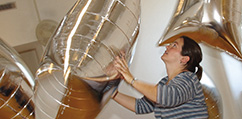 A museum volunteer handles large rectangular mylar balloons for an interactive space.