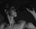 A side view of a shirtless muscular young person drinking from a glass bottle.