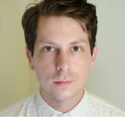 Headshot of artist Adam Milner standing in front of a light-colored wall