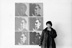 Artist Ai Weiwei stands in front of six portraits of Andy Warhol and mimics his pensive pose