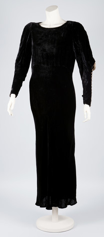 A photograph of a long-sleeved, ankle length black dress on a mannequin.