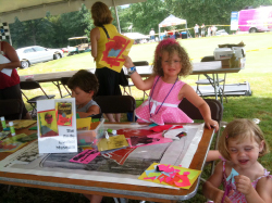 Three children create art underneath a tent