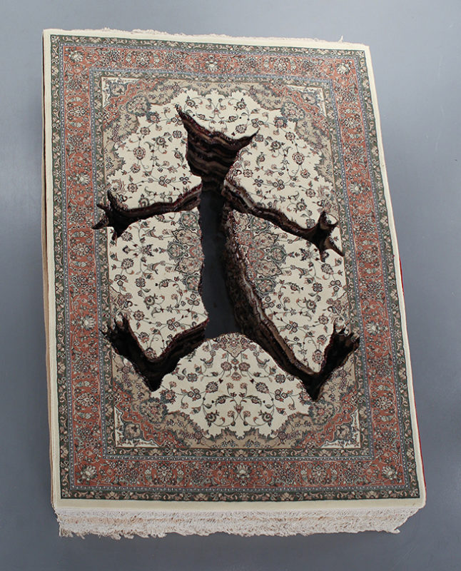 A large stack of Persian carpets with a cartoon-like figure cut out of the middle of it.