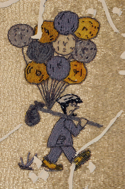 A detail of a canvas that shows a man in a gray suit and gray hat carrying a stick with a bag and ten different colored balloons on the end on a gold background. The artwork is made with hand-embroidered beads, paint, plastic, crystals, glitter, and glaze.