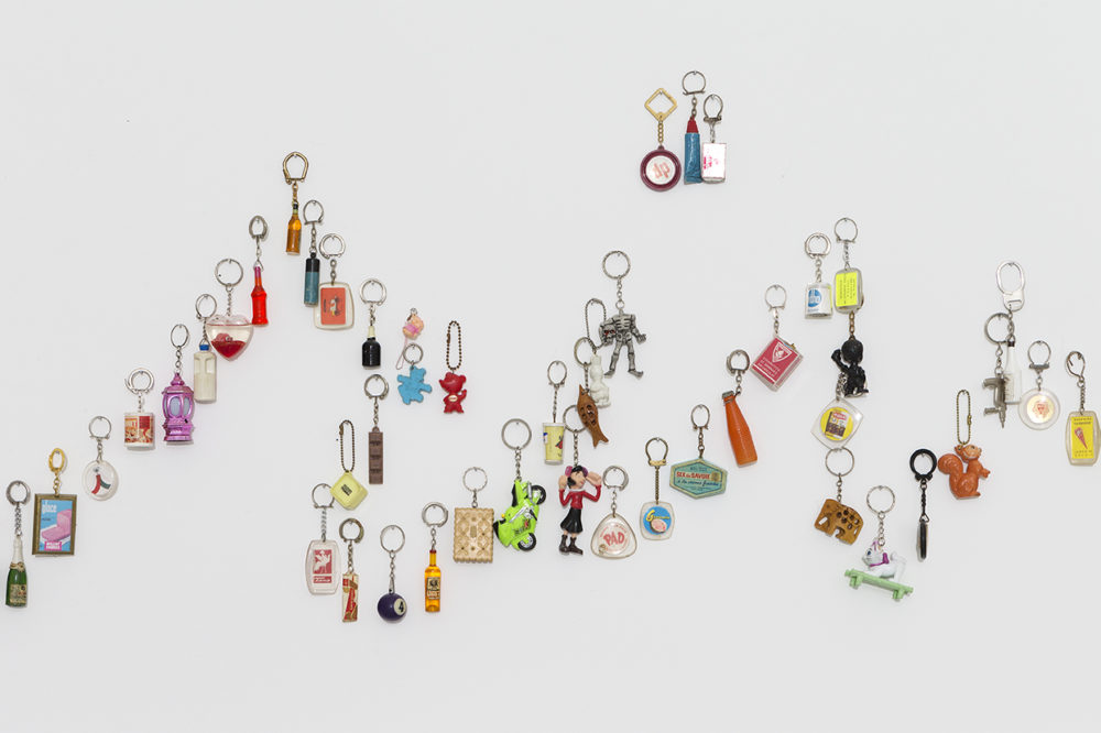 A detail of an artwork of keychains of many shapes and colors on the wall.