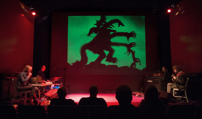 Viewers watch the musical ensemble Dungen in conjunction with the projection of an animated film.