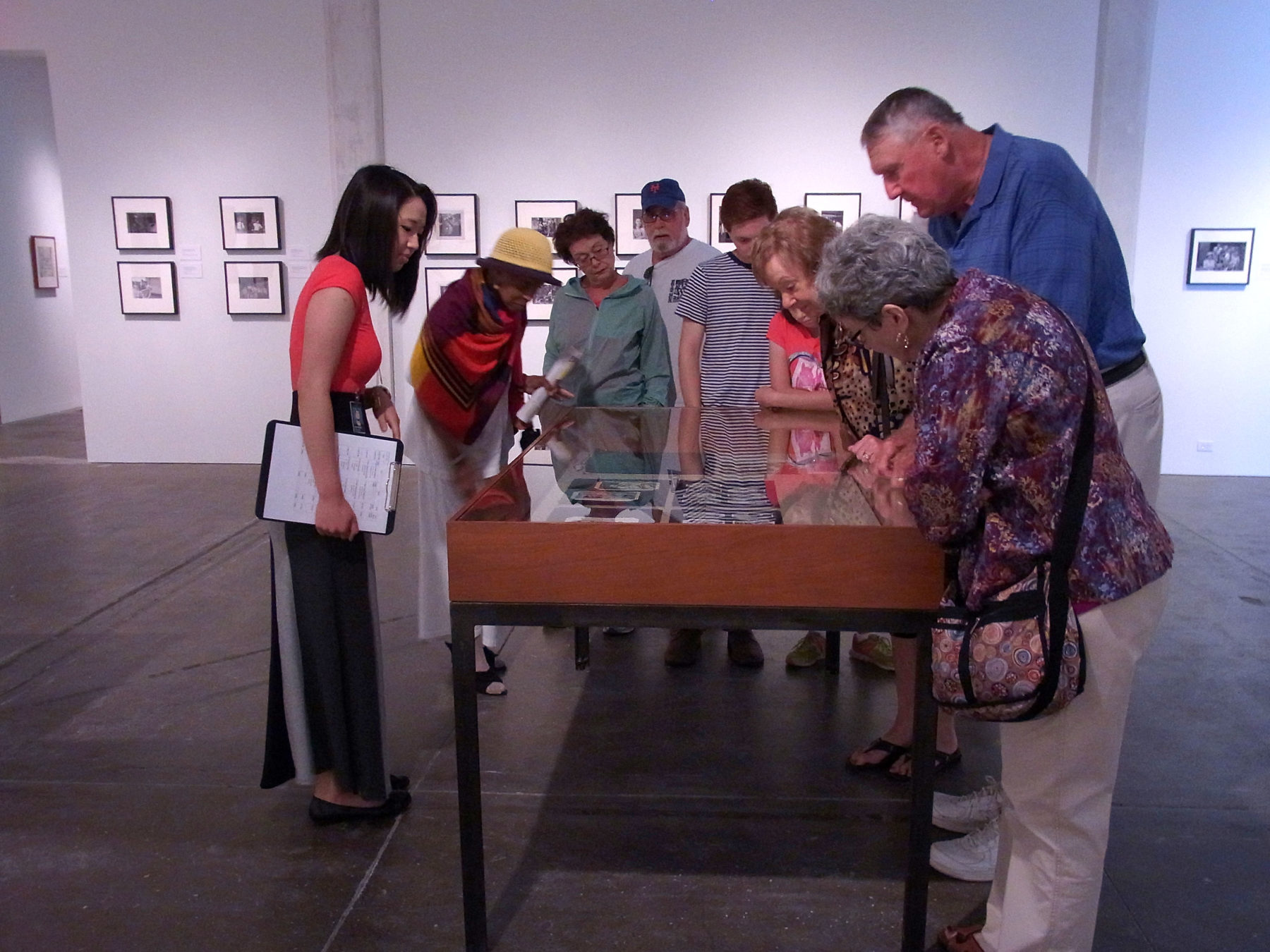 A group of people of lean over a display table in one of the Andy Warhol Museum galleries.