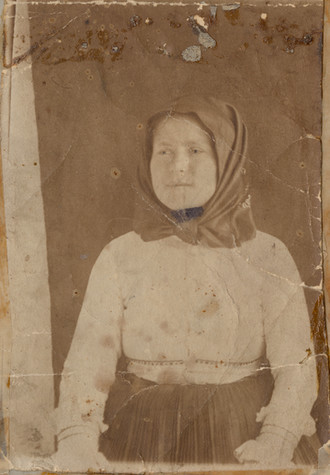 A faded photograph of a young woman wearing a scarf around her head.