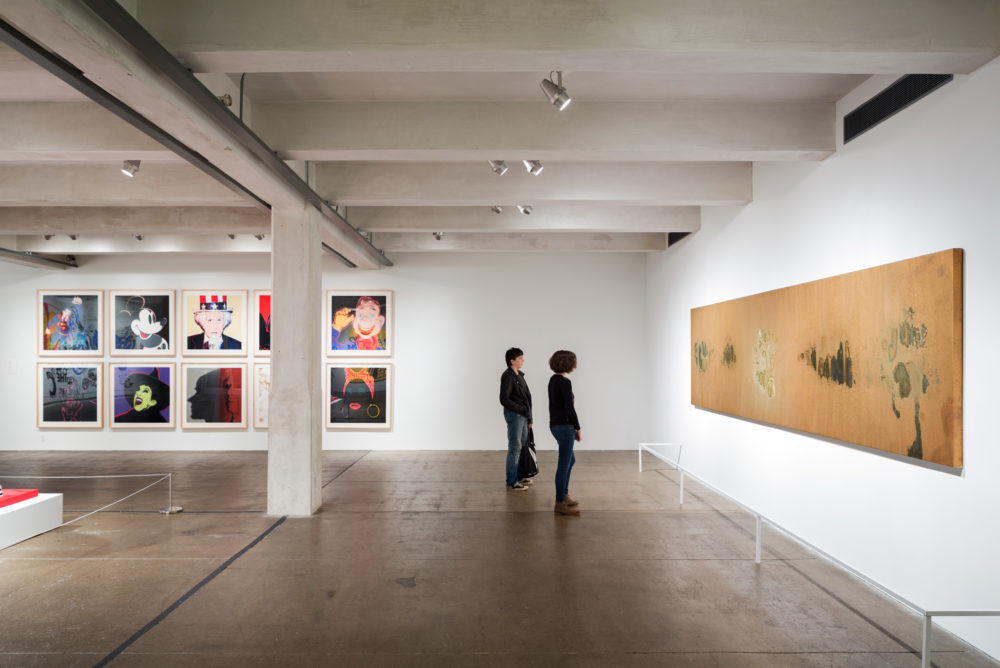 Two visitors examine a large oxidation painting in the Andy Warhol Museum.