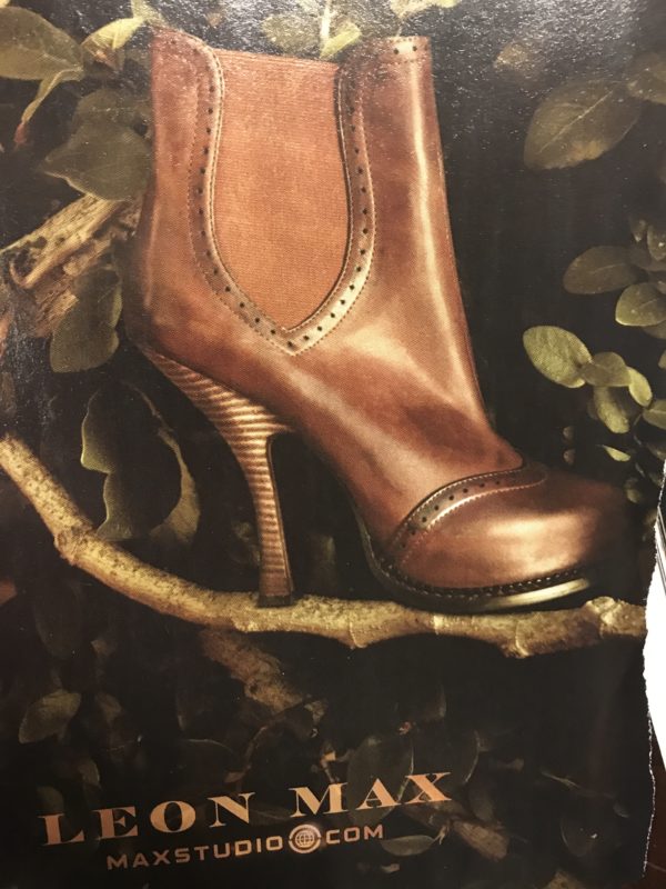 A magazine advertisement for a pair of Leon Max shoes. The shoe, a brown leather, high-heeled ankle boot, is pictured sitting on a branch, surrounded by leaves.