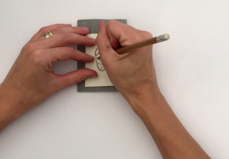 A student traces an image of a strawberry taken from Andy Warhol's early commercial work onto a small square of carbon paper, only slightly larger than the tracing of the strawberry itself.