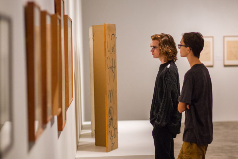 Two young men look at artwork in a gallery