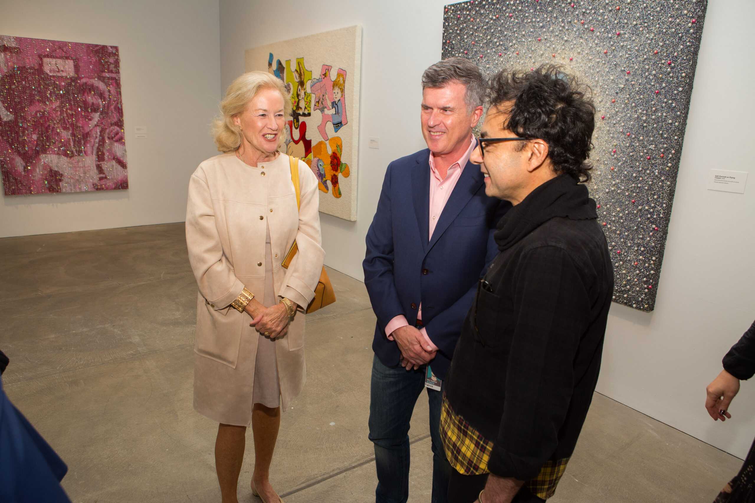 A Portrait Society and Board Member stands with Warhol Museum Director, Patrick Moore and artist, Farhad Moshiri as they look on to one of the artist’s featured pieces in the show.
