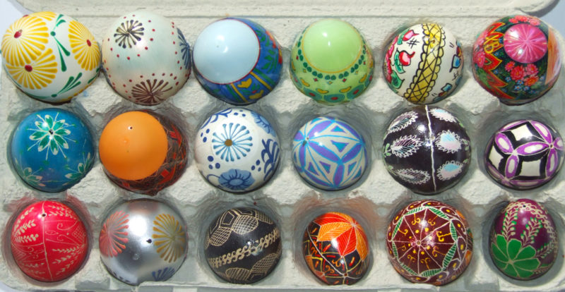 Carton of Eighteen multi-colored Pysanky Easter eggs with various detailed designs.
