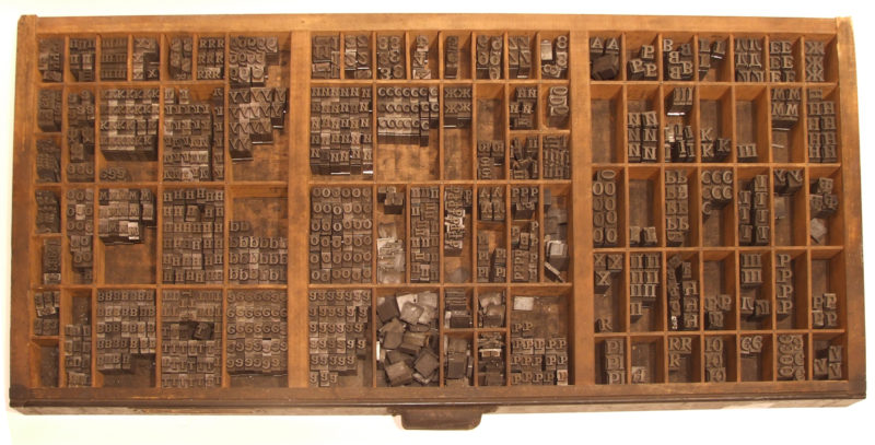 Overhead view of box with various small compartments containing type-letters from the Cyrillic alphabet.