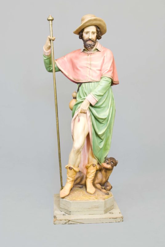 Front view of statue of San Rocco. San Rocco wears a pink and green layered robe.