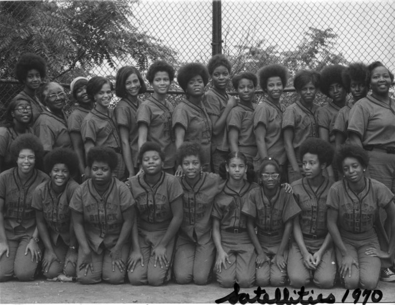 Black and white photograph of United Black Front sponsored softball team. The photograph features twenty four African American women standing and seated in front of a fence.