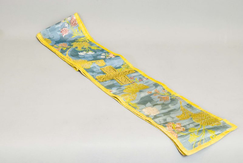 Front view of Swaddling cloth. The cloth has an ornate, floral pattern on a blue background, with a yellow border.