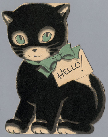 Greeting card in the shape of a black kitten, with fuzzy black flocking. The kitten has blue eyes and a blue bow around its neck with a tag that says Hello!