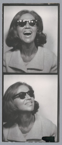 This is a double black and white photo from a photo strip taken in a photobooth. The image is of a woman with shoulder length brown hair wearing sunglasses. In the top photo, she is looking out at the camera smiling, while in the bottom she is looking up and to her left.