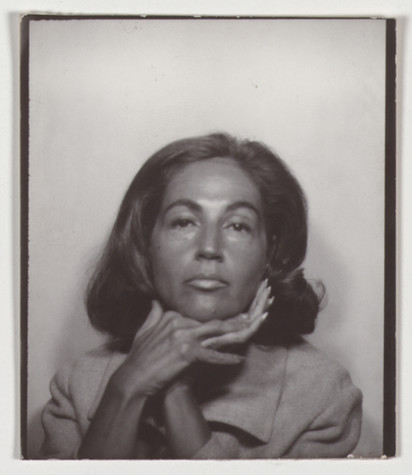 This is a single black and white photo from a photo strip taken in a photobooth. The image is of a woman with shoulder length brown hair resting her chin on folded hands.