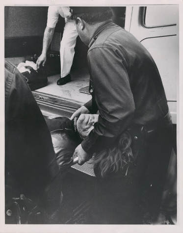 This black-and-white photograph shows Andy Warhol, unconscious, being lifted into an ambulance by a police officer after he was shot.