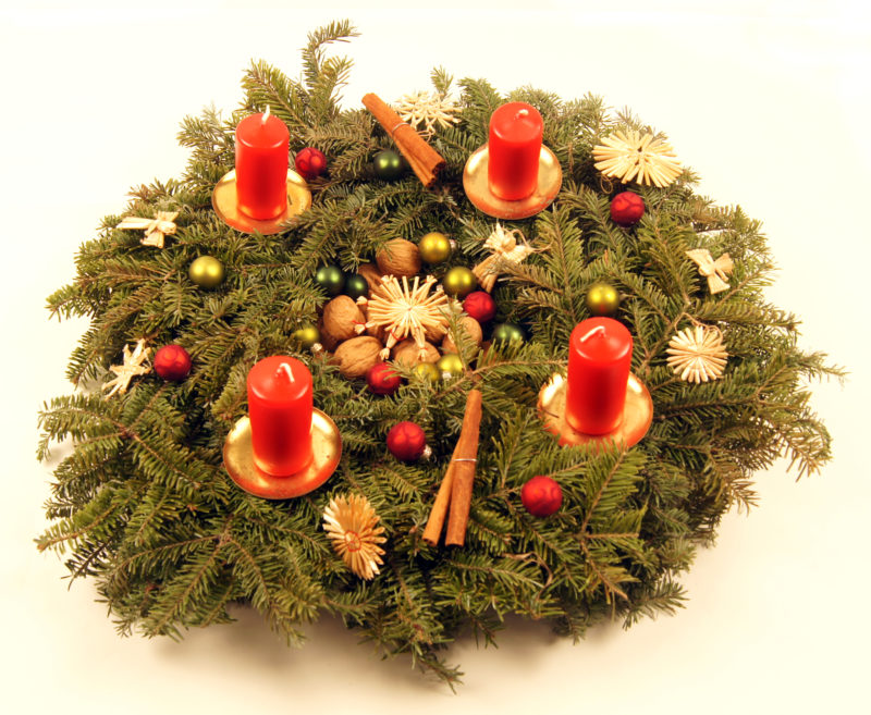Image of advent wreath with unlit red candles and red and gold ornaments.