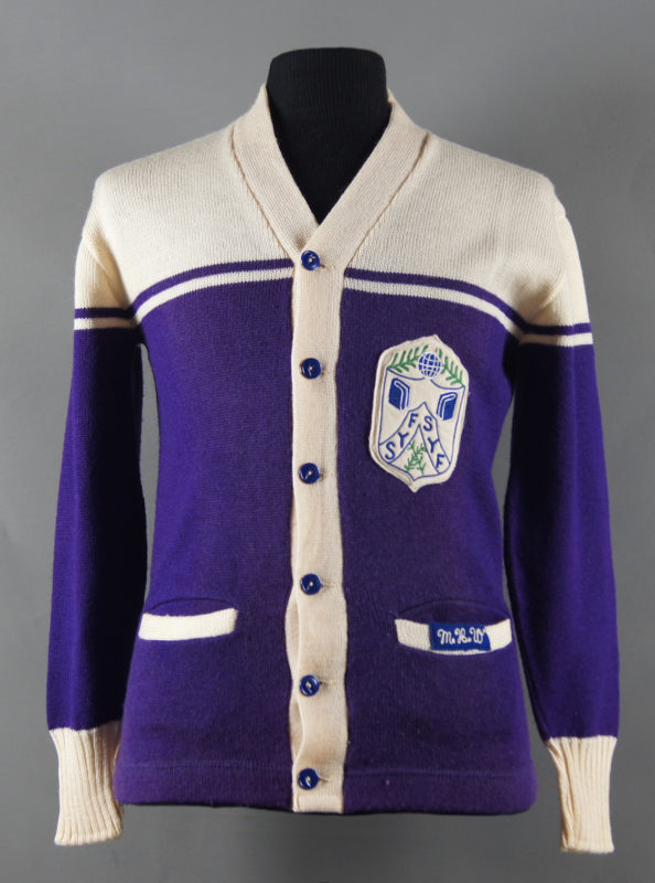 Front view of a Spicer Youth Forum cardigan sweater. The sweater is cream and purple with pockets and a Spicer Youth Forum insignia on the right.