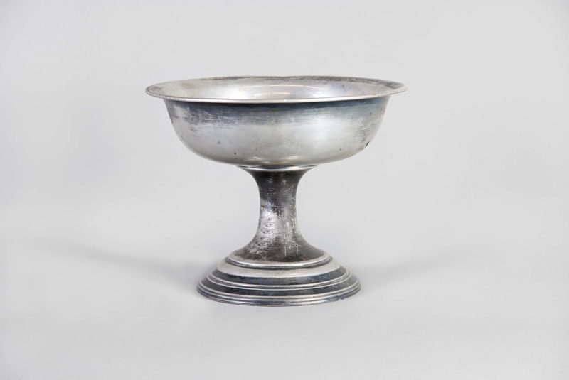 Front view of a baptismal font made of silver metal.