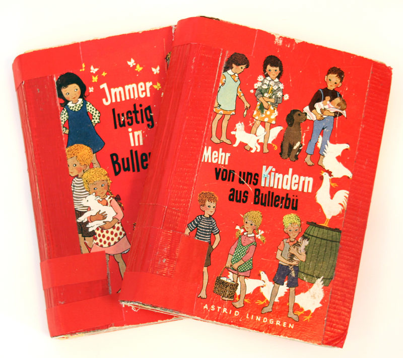 Front view of two red children’s books. The titles are in German and are surrounded by images of children and various animals.
