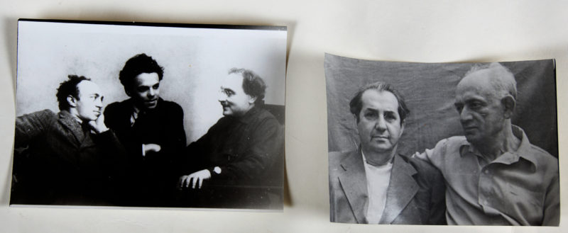 View of two black and white photographs. The photo on the left features three men seated and looking at one-another, mid-conversation.The photo on the right features two older men posed together for the camera.