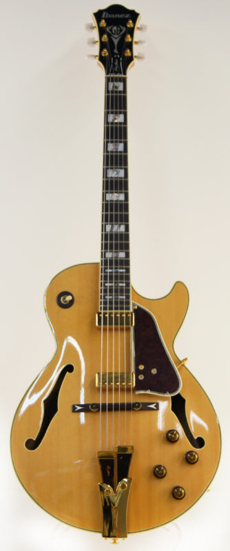 Full view of Ibanez guitar, model GB10. The body of the guitar is light brown, and the neck and head are black with white and silver frets.