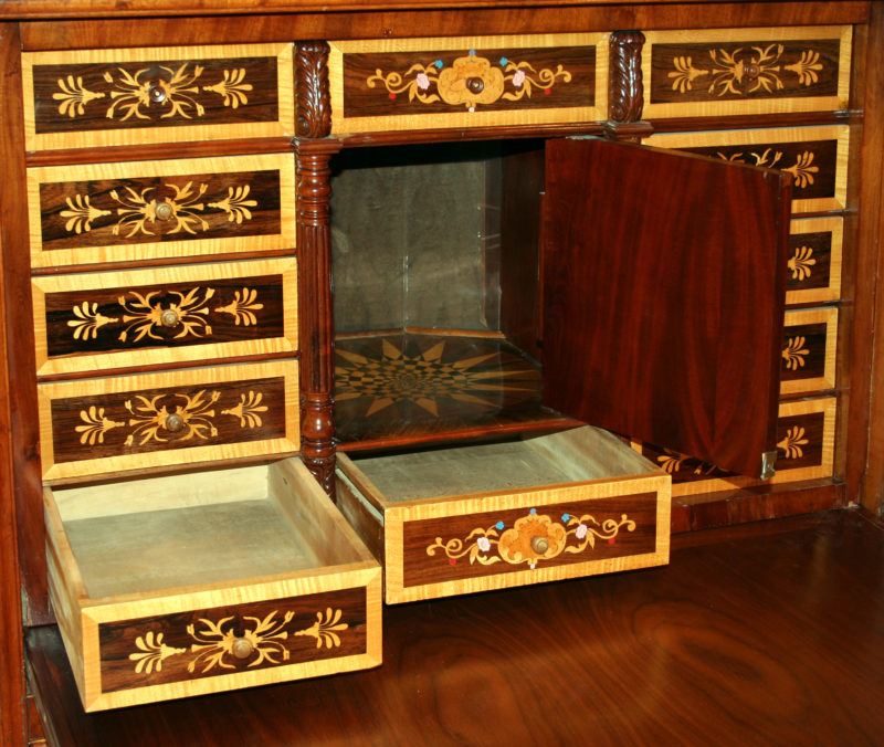 The boxes that make up the design of the desk’s backing are opened, revealing that each box is a secret compartment. The rectangular boxes become drawers that extend outward, and the square box opens to become a miniature storage space.