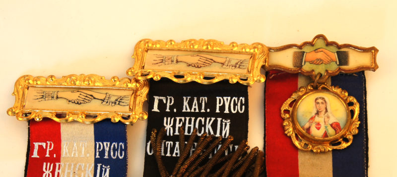 Close-up view of the top halves of three insignias. The insignias are topped with images of shaking hands