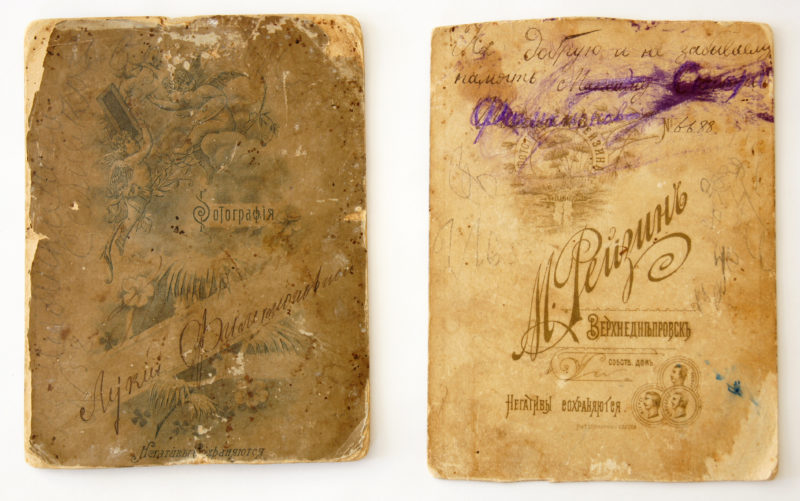 View of reverse sides of photo backings. There are writings and designs that have faded with age.