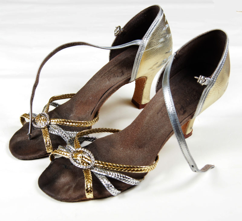 Close-up view of a pair of high-heel shoes with shiny silver and gold straps.