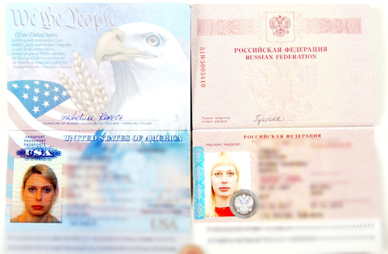 Scan of two open passports, side by side. The passport on the left is American and the passport on the right is Russian; both feature the same woman with a different haircut.
