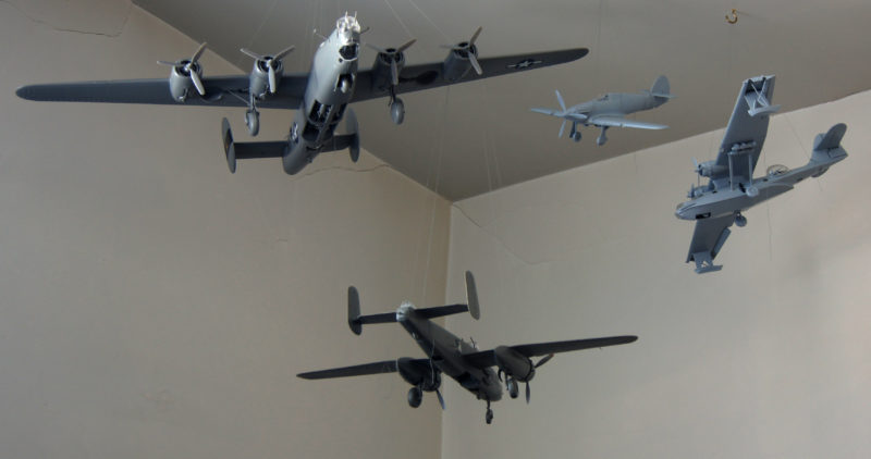 Image of four model airplanes of different models, hanging from a ceiling.