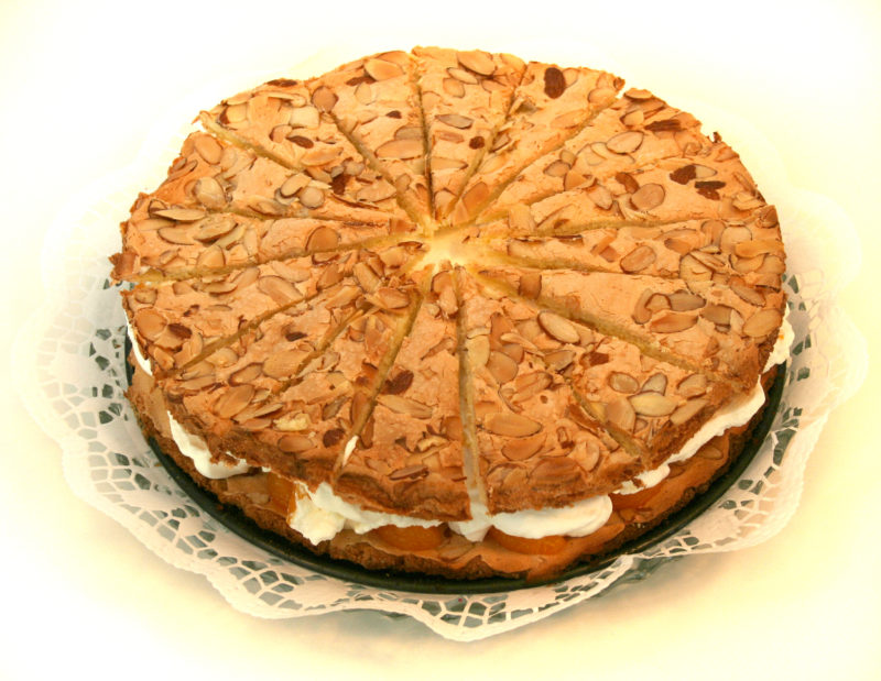 Photo of traditional German Mandelkuchen cake. The cake is filled with cream and topped with almonds.