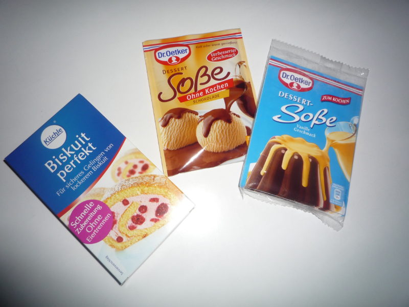 Front view of three packets of dessert mixes. The packets display images of the dessert they create along with brand names (Kuchle and Dr. Oetker) and descriptions printed in German.