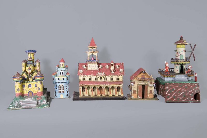 Front view of presepio miniatures. There are five village buildings of various sizes and colors lined up together.