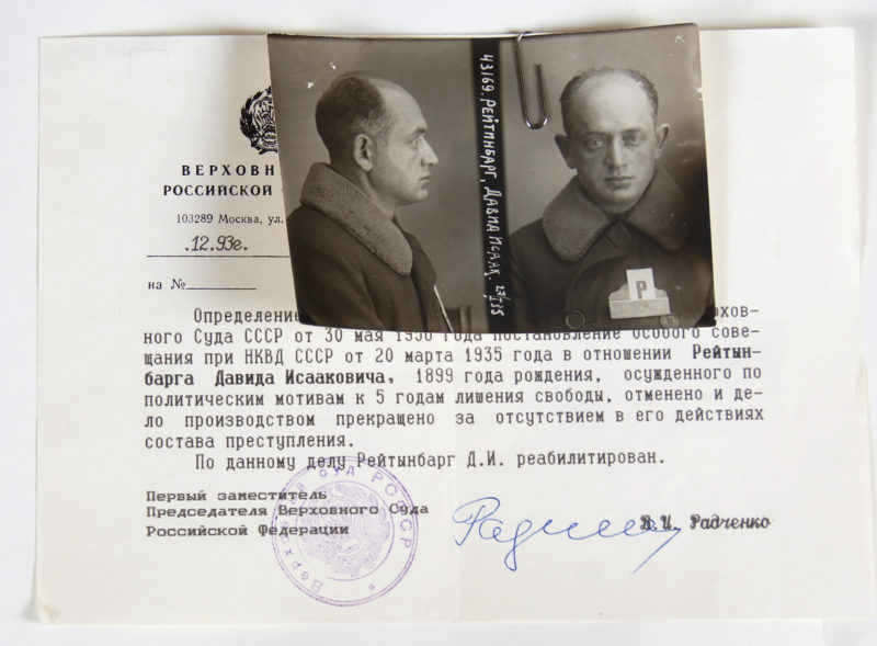 View of mugshot photo paperclipped to a certificate typed in Russian. The certificate is signed and stamped.